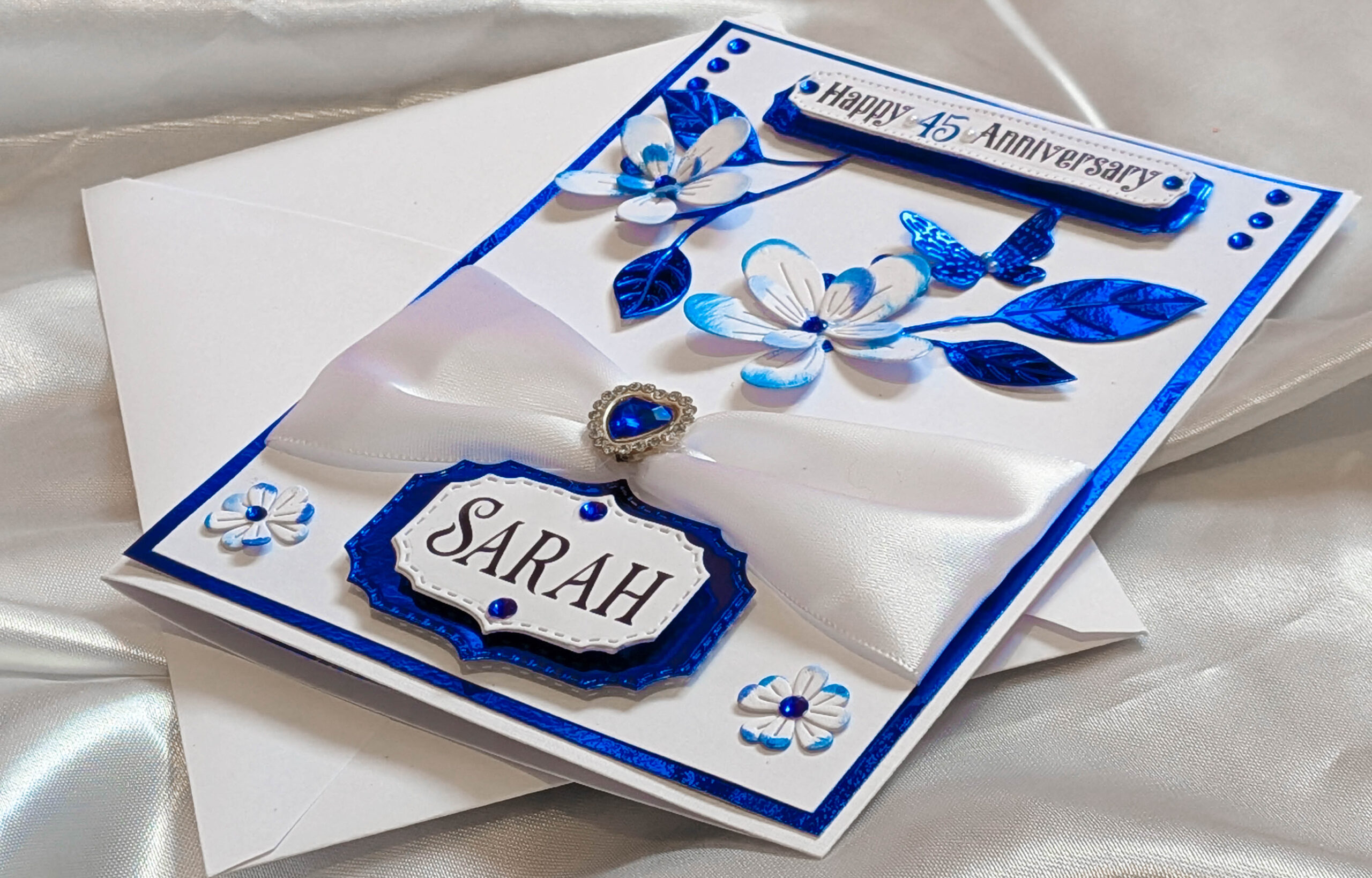 High-angle overview of an entire handmade 3D greeting card on a silky white background.