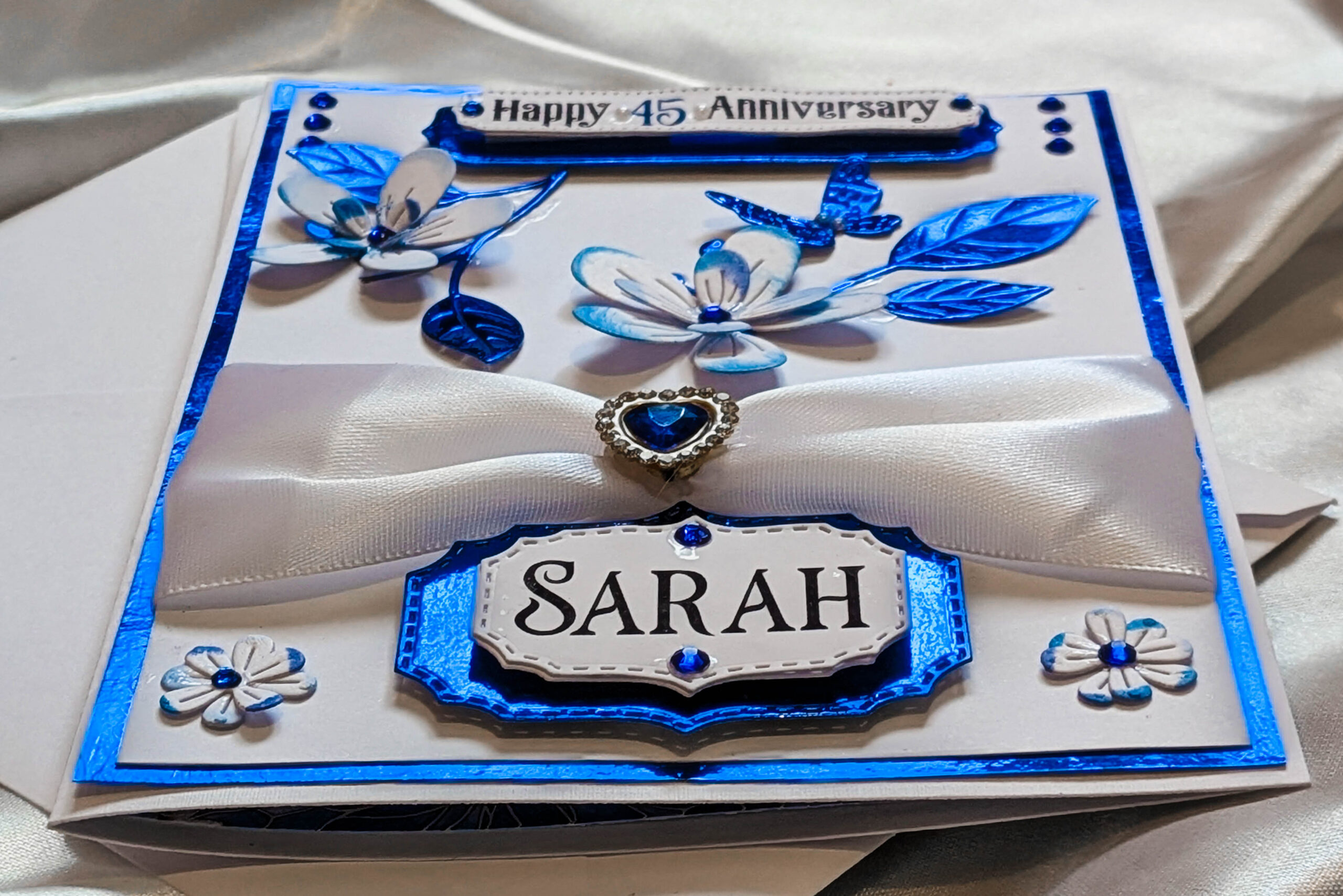 A close-up, angled photograph of a custom handmade card featuring the personalized name 'SARAH'