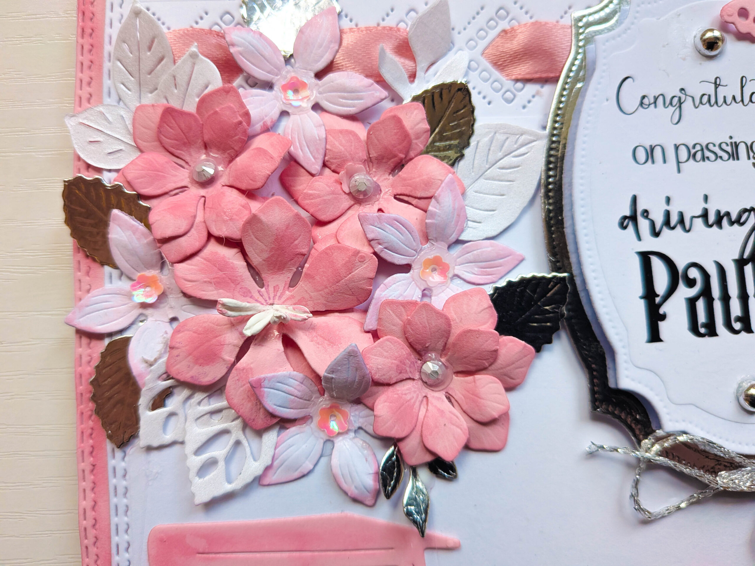 Detailed view of handcrafted layered pink paper flowers with sparkling crystal rhinestone centres and silver filigree leaves.