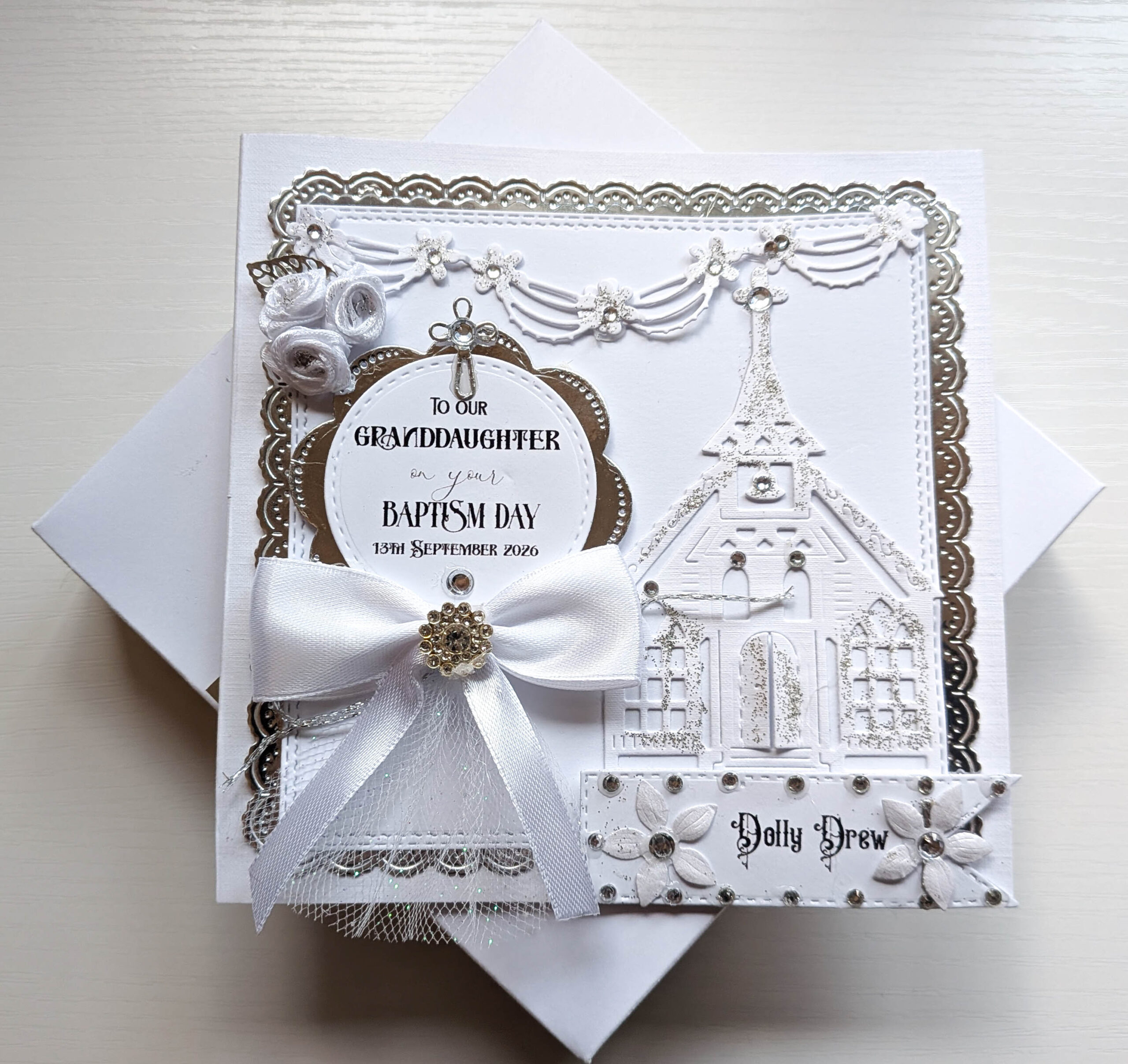 Personalised luxury baptism card resting upright on its decorated white keepsake presentation box.