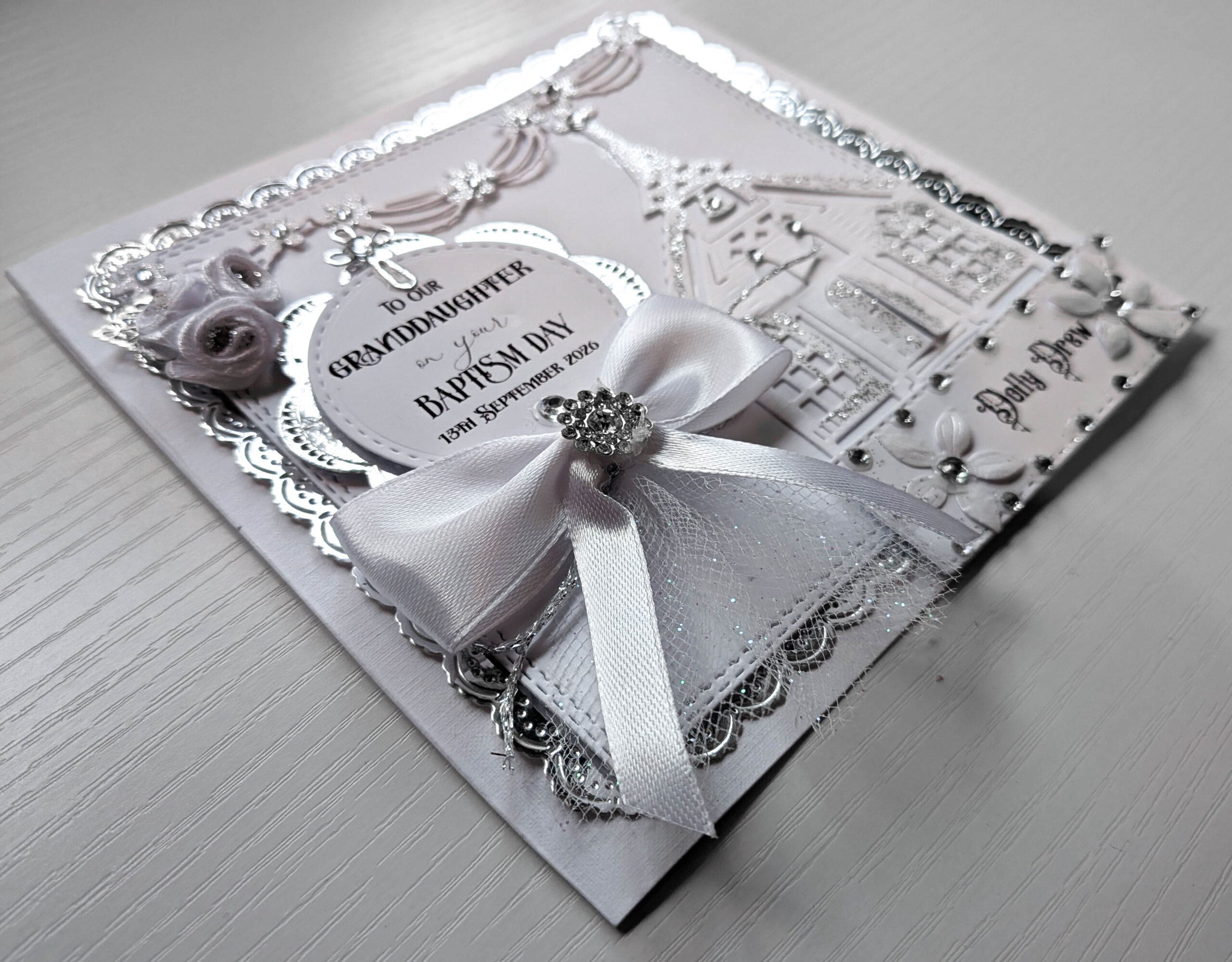 Handmade personalised luxury christening card showing 3D church, white satin bow, and silver scallop trim